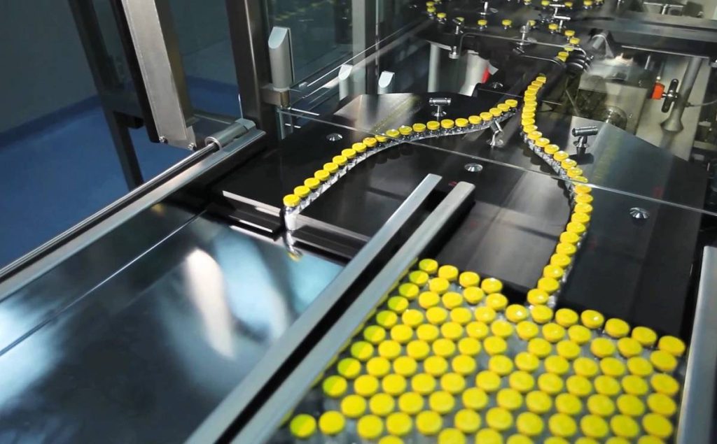 Un sistema de transporte industrial muestra botellas moviéndose en una línea de producción con piezas cortadas con láser.