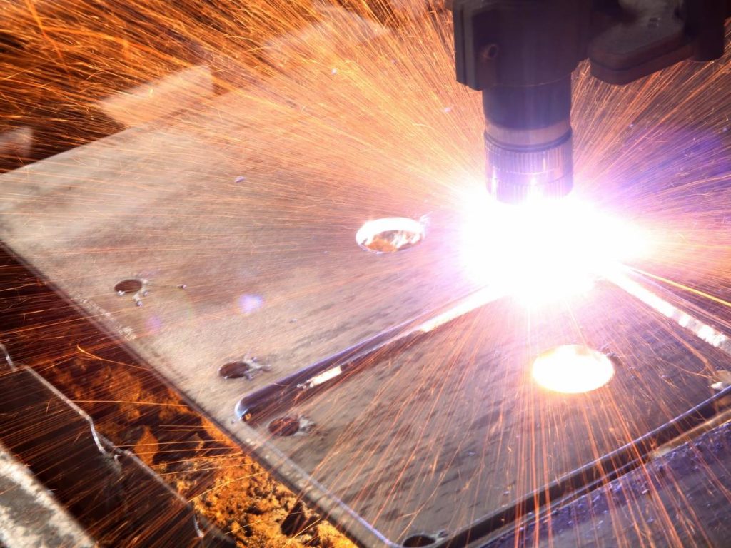 Una máquina de corte por plasma generando chispas mientras corta una placa de metal.