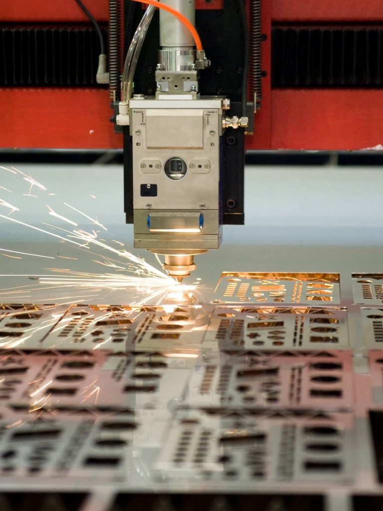 Una máquina cortadora láser trabajando sobre metal, generando chispas.