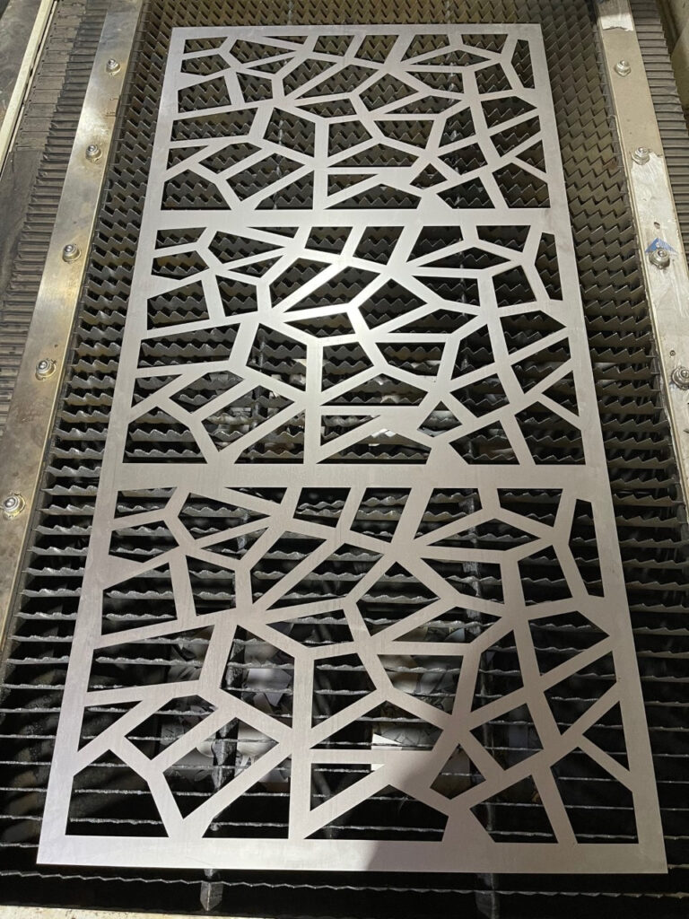 Diseño de panel metálico cortado con láser, con un patrón geométrico intrincado.